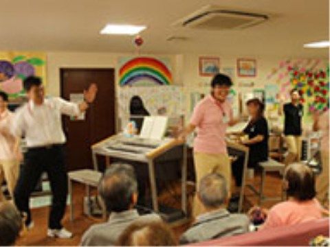 入居者様が集い、スタッフがリードをして一緒に歌っているレクリエーションの様子