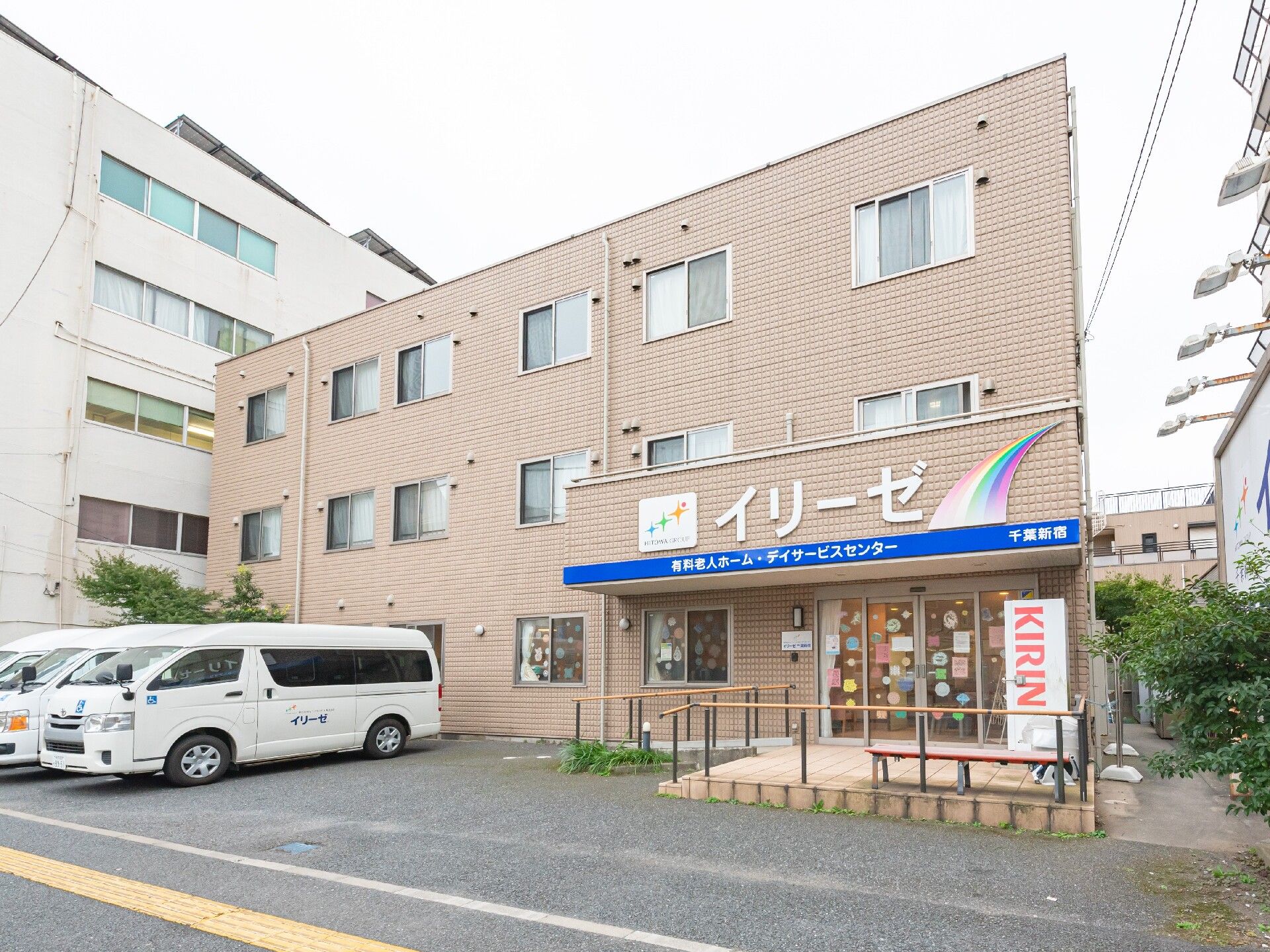 ガラス張り扉前のゆったりとしたスペースに、植木や花のプランターを並べて置いてあるエントランス