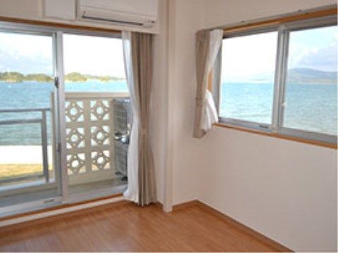 沖縄の青い海が広がる景色をより堪能できる角部屋の居室。窓のすぐそばまで海が広がっているような感覚を覚える。