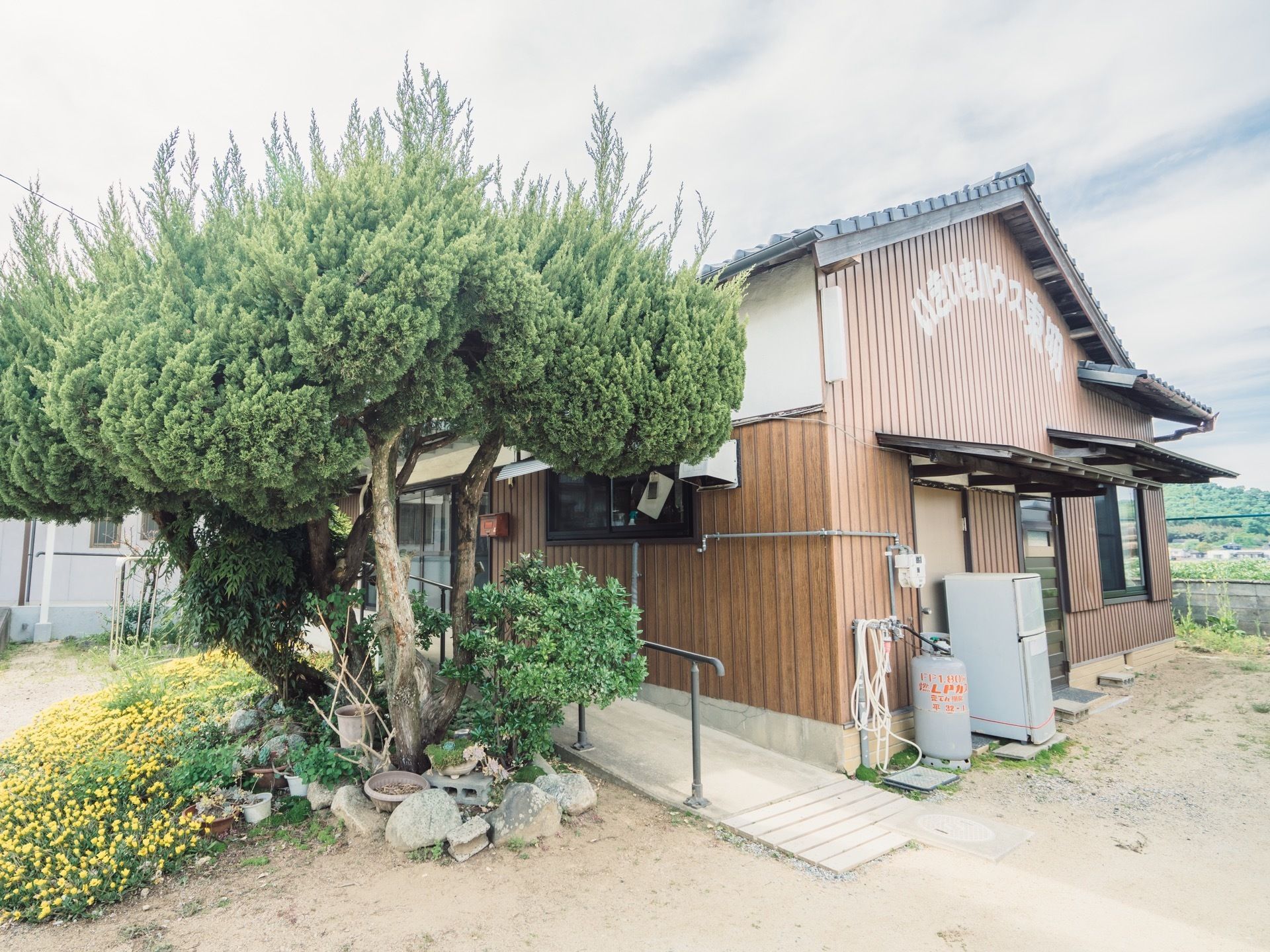 建物のサイドは、白と茶の２トーンカラーでデザインされている。手すり付きのスロープも備えつけられている。