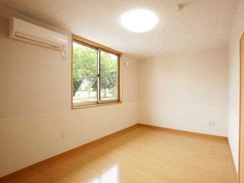 エアコン１台と照明がついた居室には大きな窓があり、そこから日差しが差し込む。床は明るい茶色のフローリング仕様となっている。