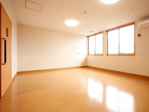 広々としたフローリングの居室には２箇所に大きな窓がついている。エアコン１台と照明が２つ設置されている。