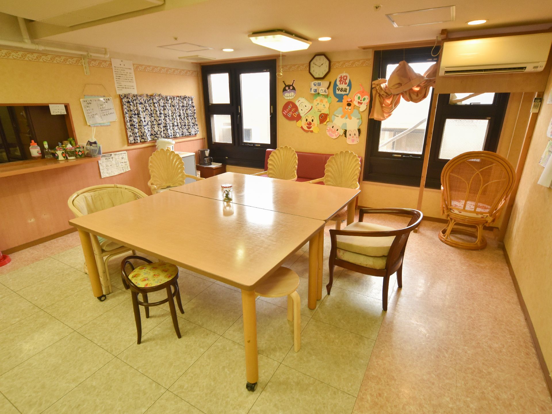 リビングの一角の写真。8人掛けのテーブルにいろいろな形の椅子がセットされている。壁にはスタッフ手作りの装飾がされている。