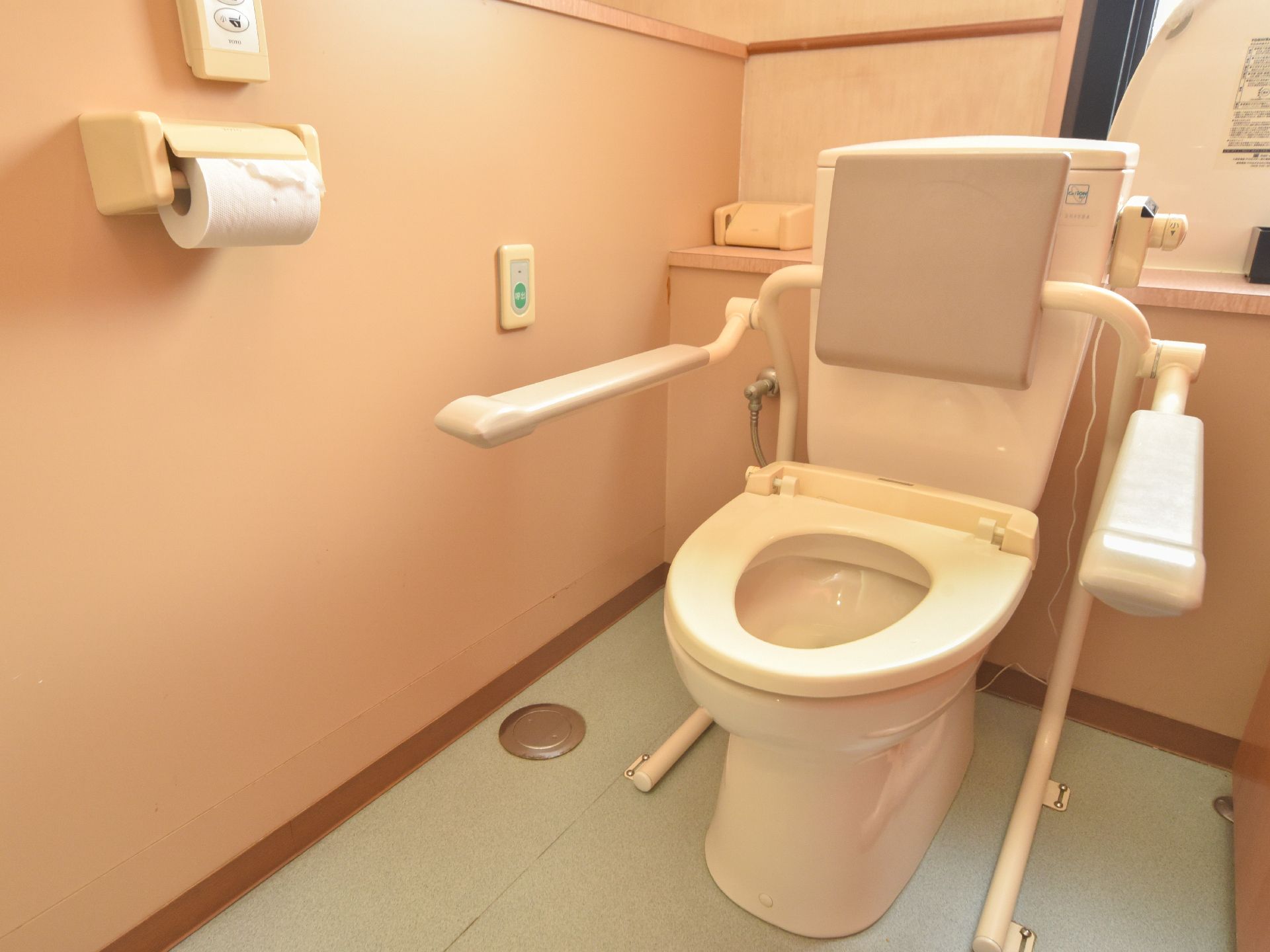 洋式トイレが設置されている。背あてとひじ掛けが追加されている。壁にはナースコールが付いているので安心。