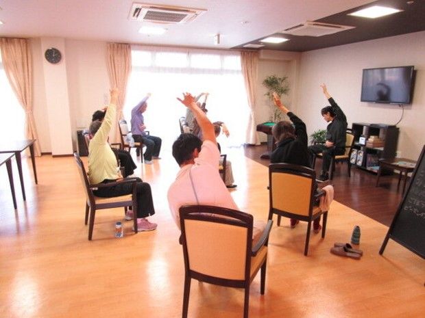 入居者が椅子に座り体操を行っている