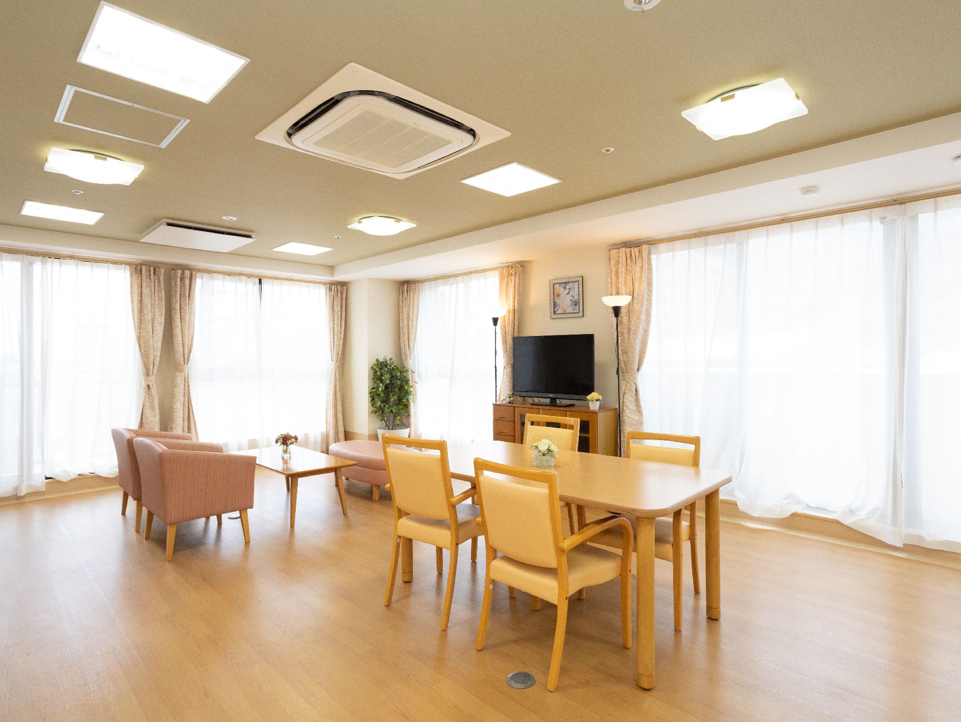 テレビが設置され、テーブルとイスが置かれている共有スペース