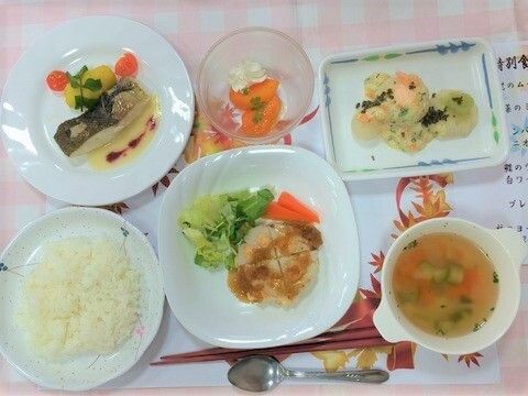 白とピンクのチェックのテーブルクロスの上にセッティングされた焼き物の料理やスープとライス