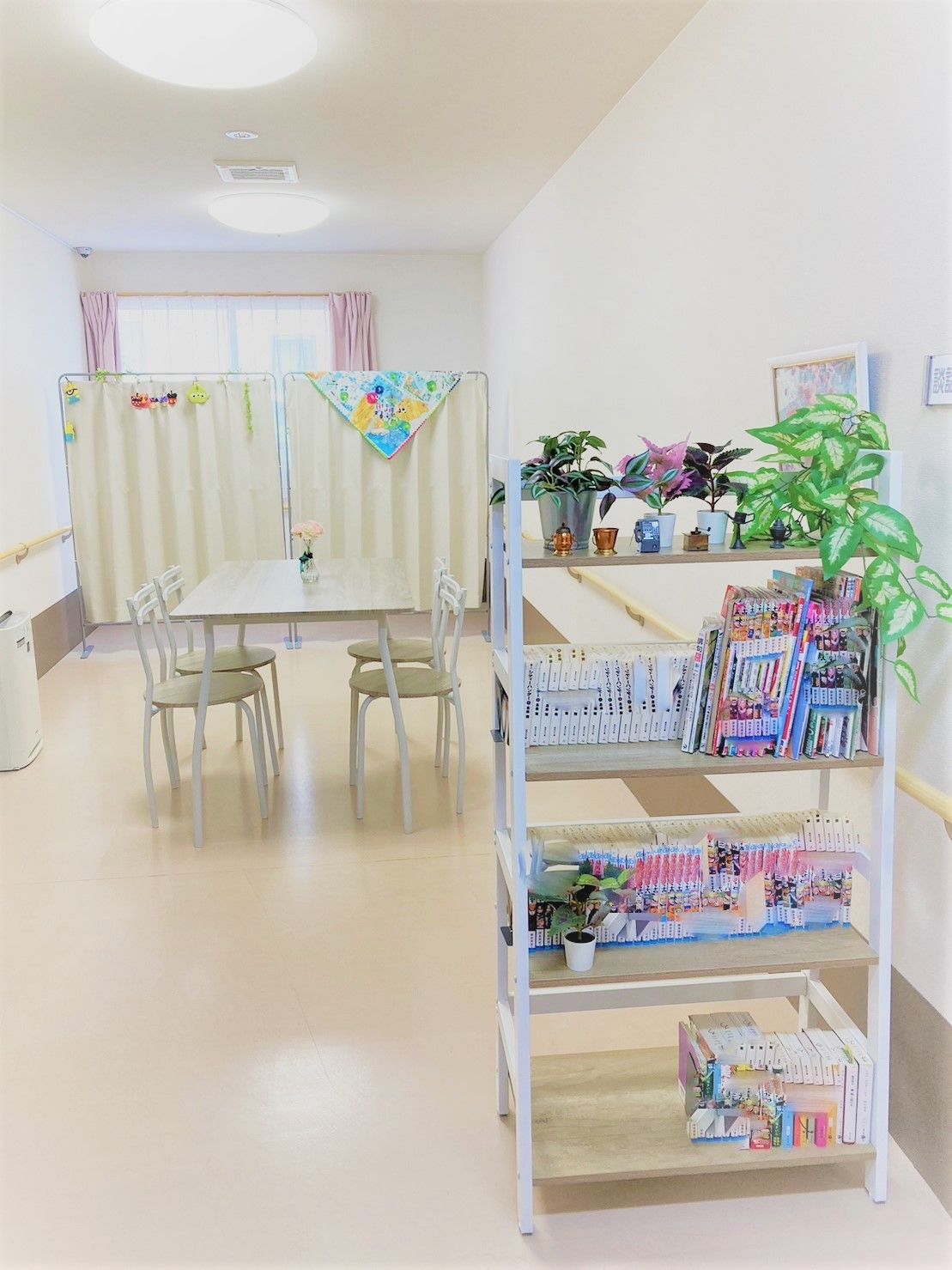 椅子とテーブルのセットが置かれている談話スペースで、手すりが壁面にぐるりと付いている。淡いグリーンの椅子がナチュラルな雰囲気である。