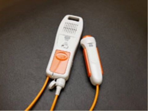オレンジのコードが伸びている、片手で操作できるナースコール
