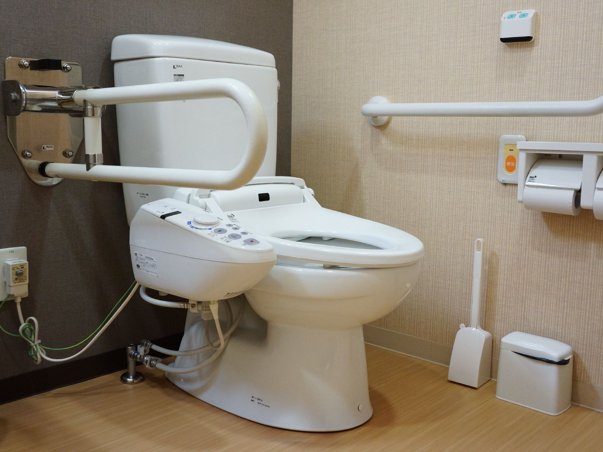 施設に用意された入居者用のトイレ。左手側の壁にはL字型の手すりとナースコール、右手側には肘掛けがある。