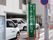 施設の敷地内の駐車場に立てられている看板。道路から見えるように行動沿いのスペースにあり、緑地に白文字で書かれている。