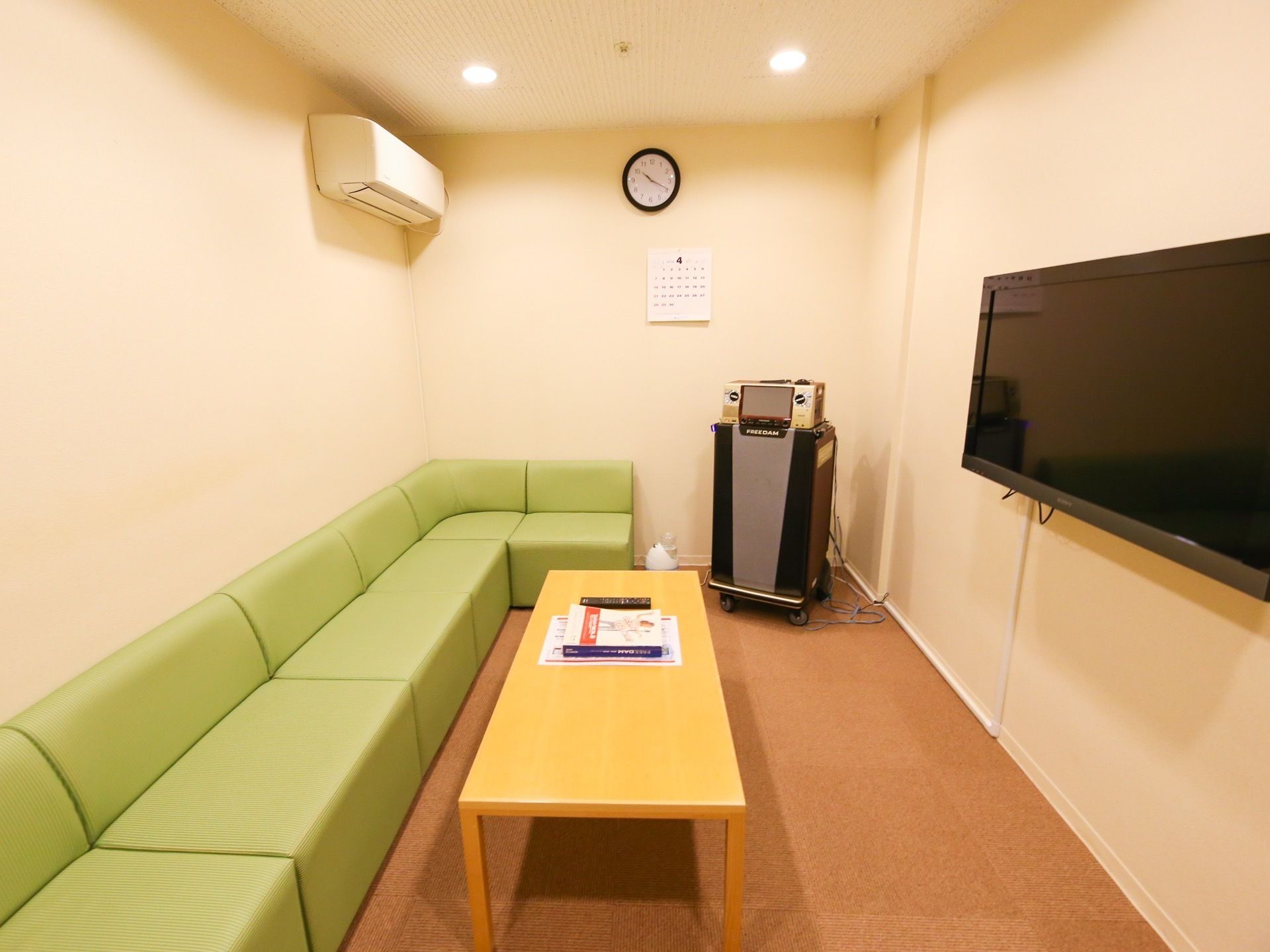 エアコンが完備された長方形の部屋に、ソファーとカラオケの機器が設置されている。ソファーの前のローテーブルにはリモコンなどが置かれている。