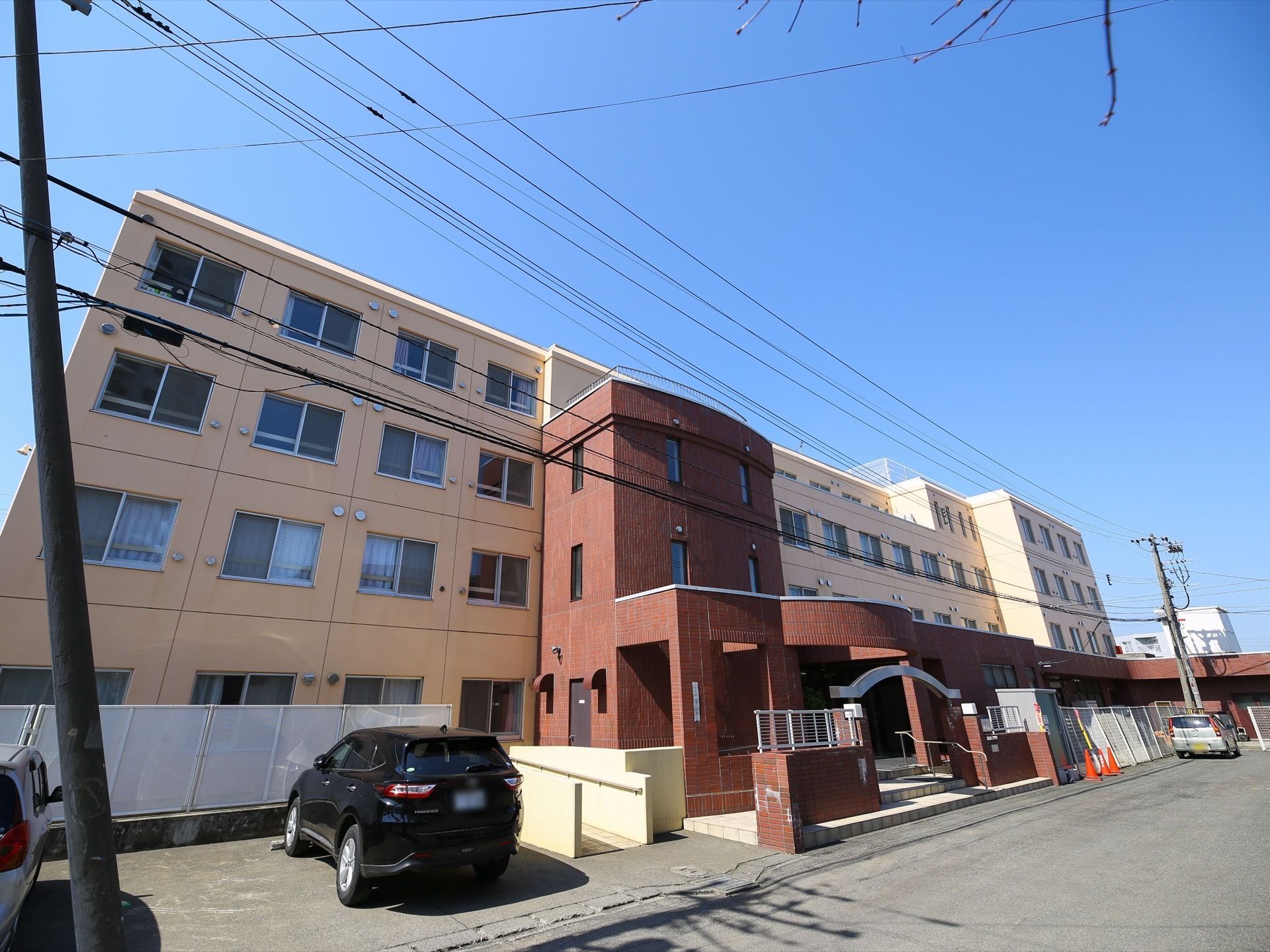 施設は４階建ての建物である。玄関ポーチなどはブラウンで、他はベージュ色のツートンカラーである。建物の前には駐車スペースがある。