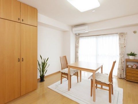 手前に背の高い衣装棚がある。部屋の中央には白いラグ敷かれ、テーブルセットと２脚の椅子が向かい合うように置かれている。