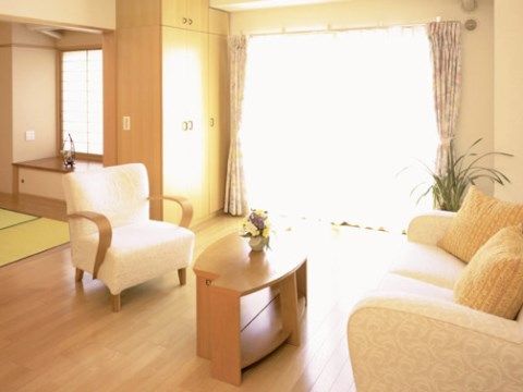 中央にあるローテーブルをはさんで、１人がけのソファチェアと２人がけのソファが置かれている。奥の壁際には両開きの衣装棚が見える。