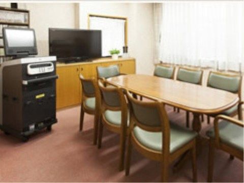 ８人がけのテーブルセットが設置され、左にカラオケセットが置かれている。奥にはテレビや、CDの並んだ棚が見える。
