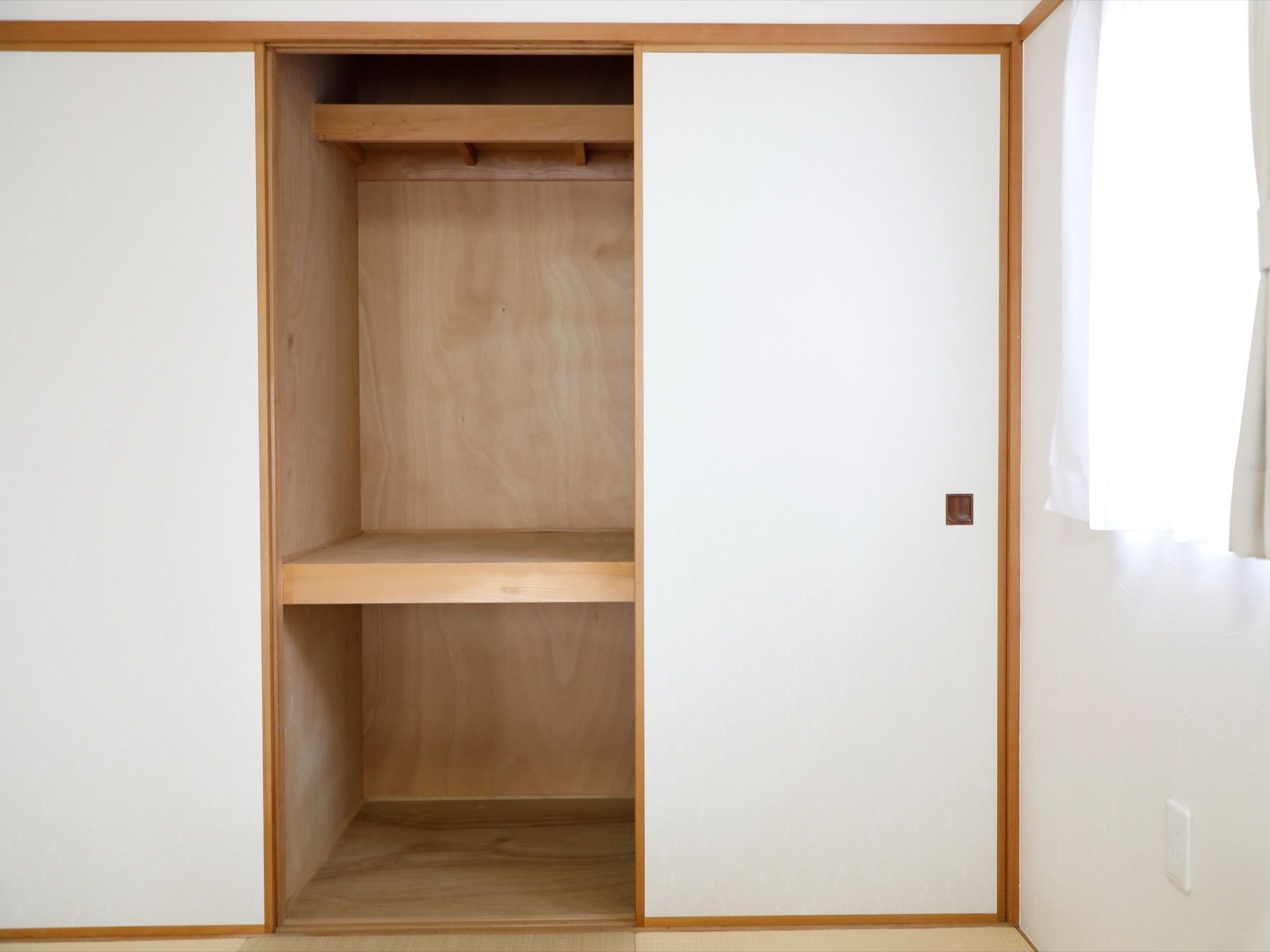 手前には白色の襖があり、開いている。中は２段になっている。右壁には窓があり、その下側にはコンセントがある。