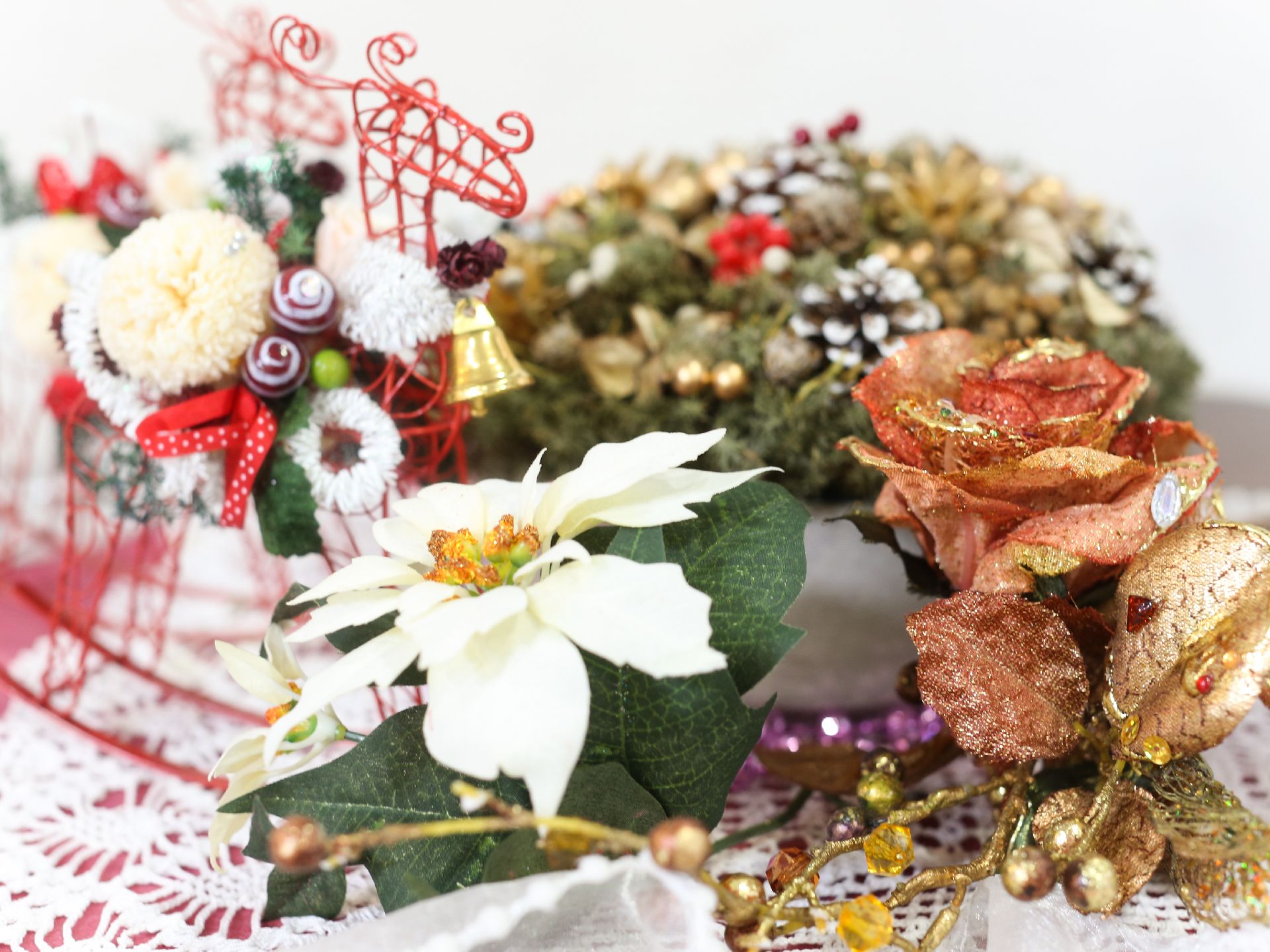 ラメ入りのバラ、白色の花、また、トナカイの形の赤色の籠にクリスマスの飾りが施されている。華やかなレイアウトである。