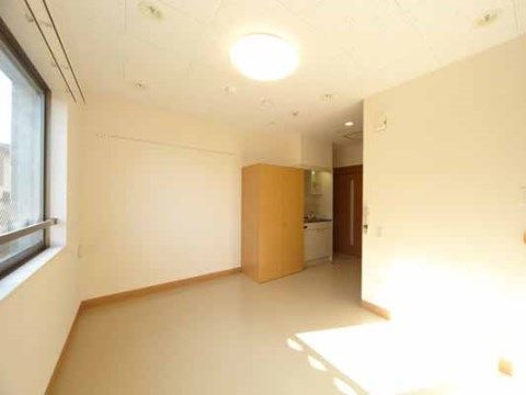 明るく広い居室である。ミニキッチンや収納家具、照明が完備されている。自然光が差し込む窓が設けられている。