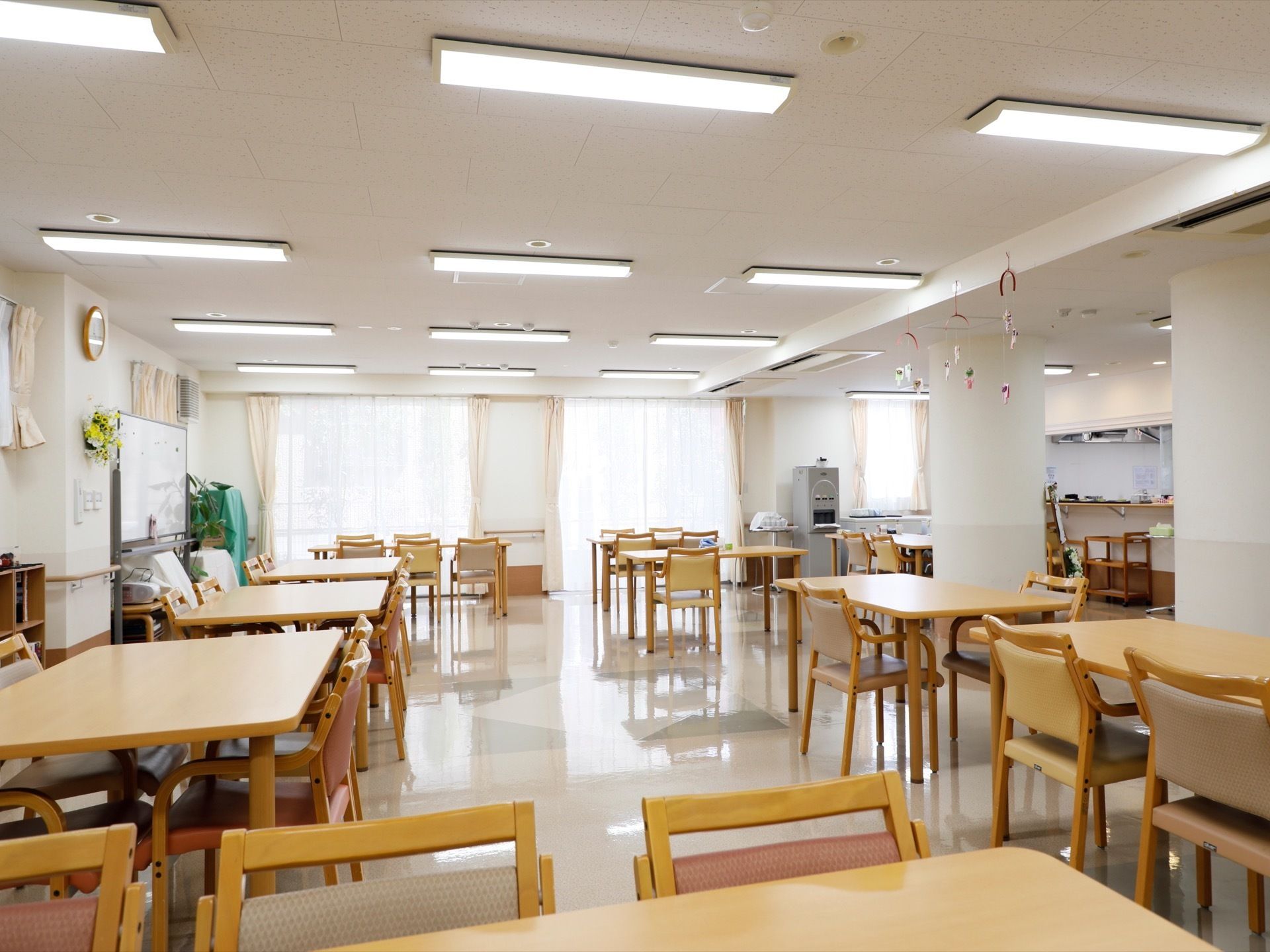 ホールには、椅子が4〜5脚のテーブルが離れて置かれてある。窓は大きく光が差し込み、自動給茶機が設置されている。