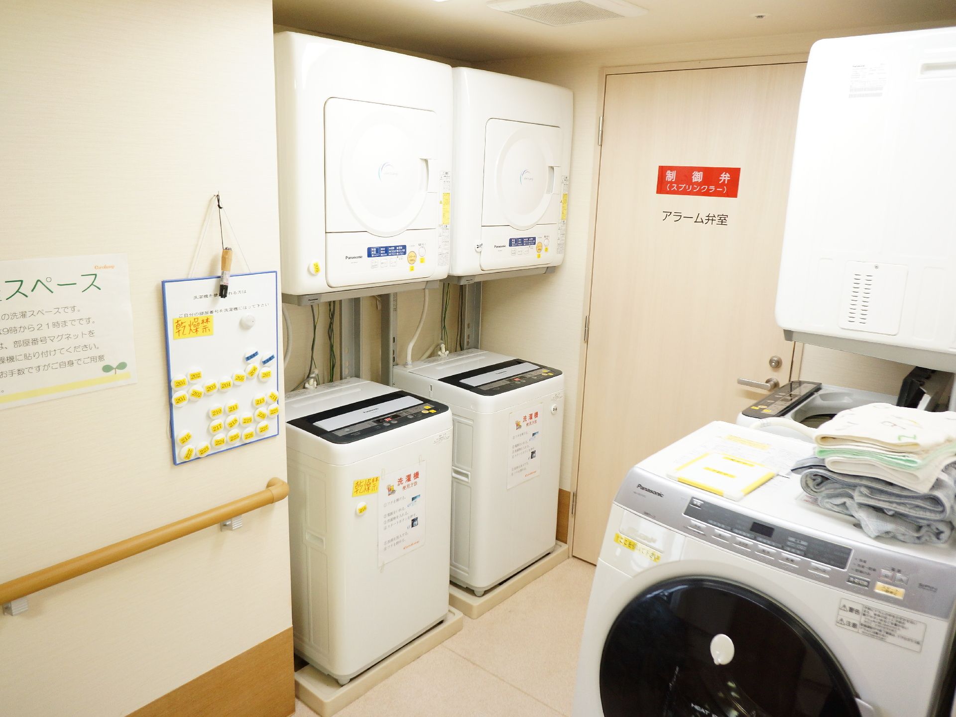 洗濯スペースには、自動洗濯機と乾燥機が数台づつ設置されている。壁には手すりが付いているので歩行も安心。