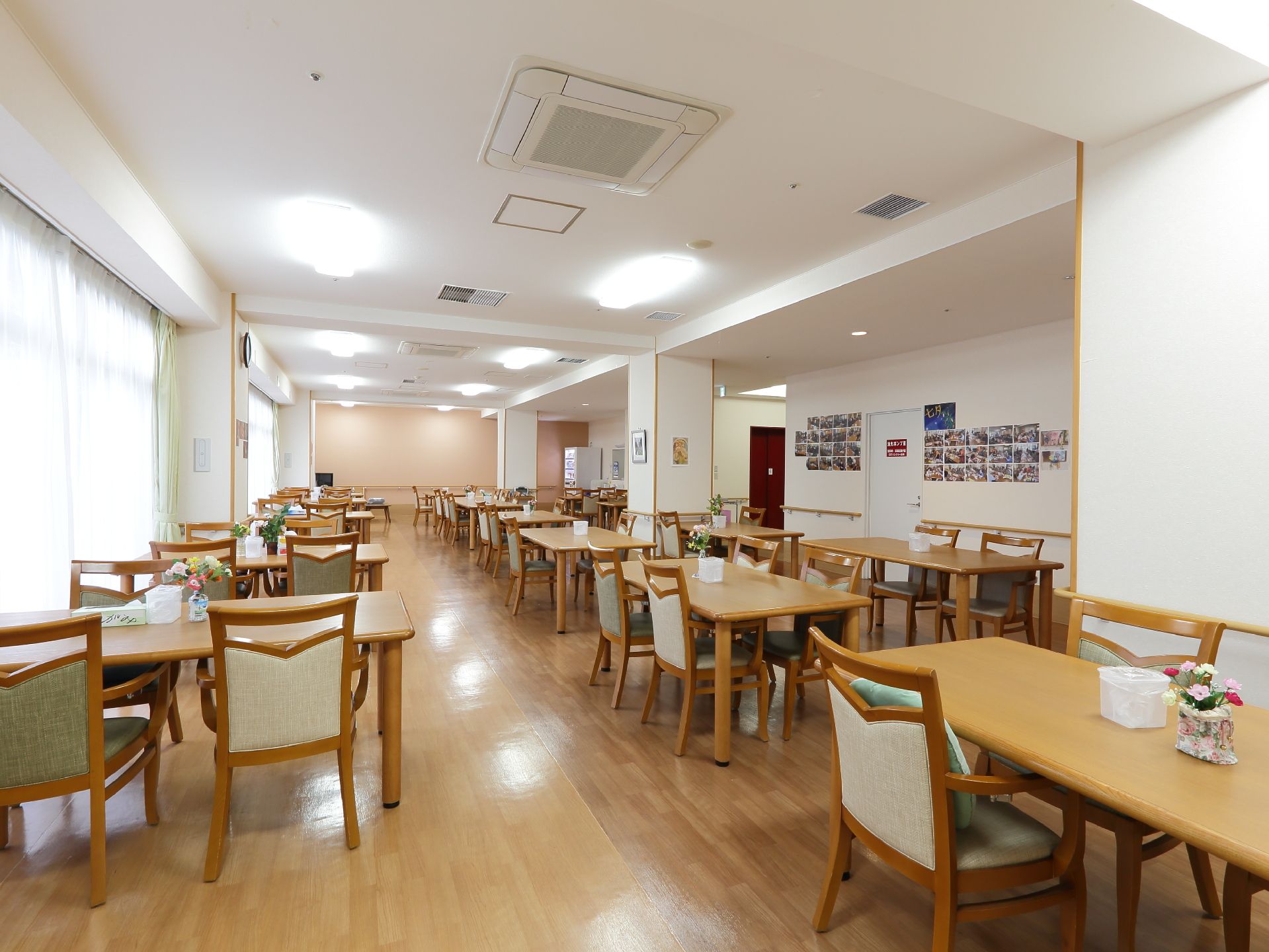 入居者らが食事を取るための広い食堂。数多くの座席が並び、それぞれのテーブルの上には花が飾られている。