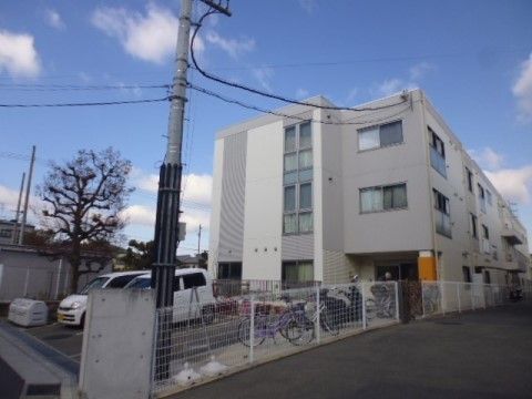 施設の建物は３階建ての住宅風で、窓が多く設置されている。隣接するスペースには駐車場と駐輪場が設けられている。