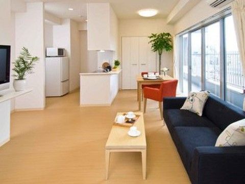 室内にはガラス引き戸からの光があふれ、フローリングの床にはテーブル、ソファが設置されている。観葉植物、テレビ、冷蔵庫なども置かれている。
