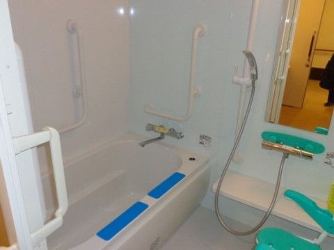 浴槽の周囲には手すりが十分に設置され安心して入浴できる。壁には緊急呼出ボタンや鏡、シャワー設備が設けられている。