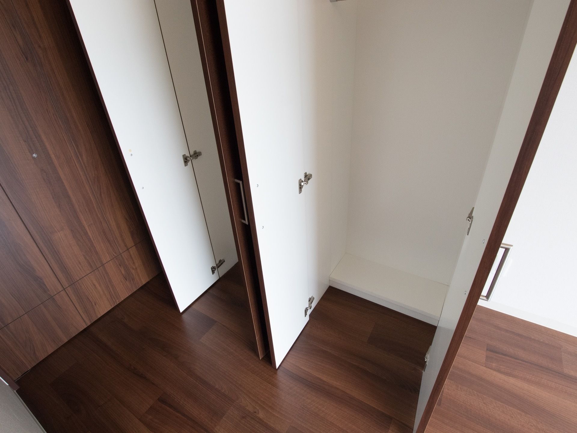 こげ茶色の木目のフローリングの床に白いクロスの部屋である。２つの観音開きの扉がついたクローゼットがある。