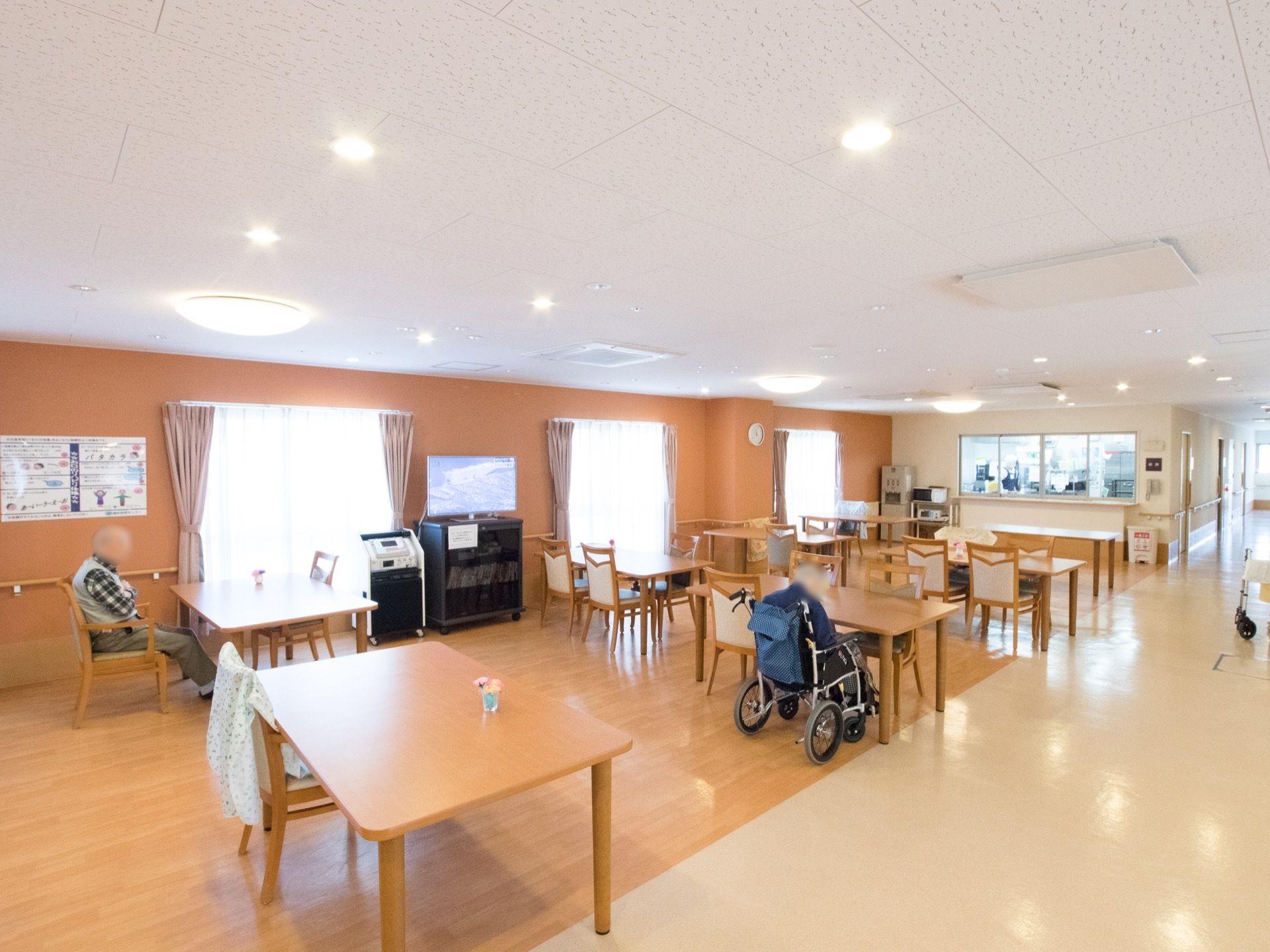 食堂の床と通路の床がオレンジ色とクリーム色に色分けされている。窓から入る光と天井に取り付けられた照明で室内はとても明るい。