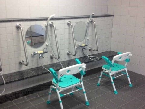 白と緑の浴室用椅子が２脚置かれている大浴場の洗い場
