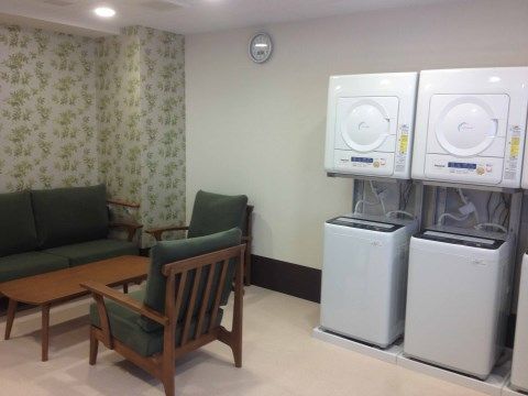 ランドリールームには全自動式洗濯機と乾燥機が設置されている。休憩用のソファとテーブルが置かれている。
