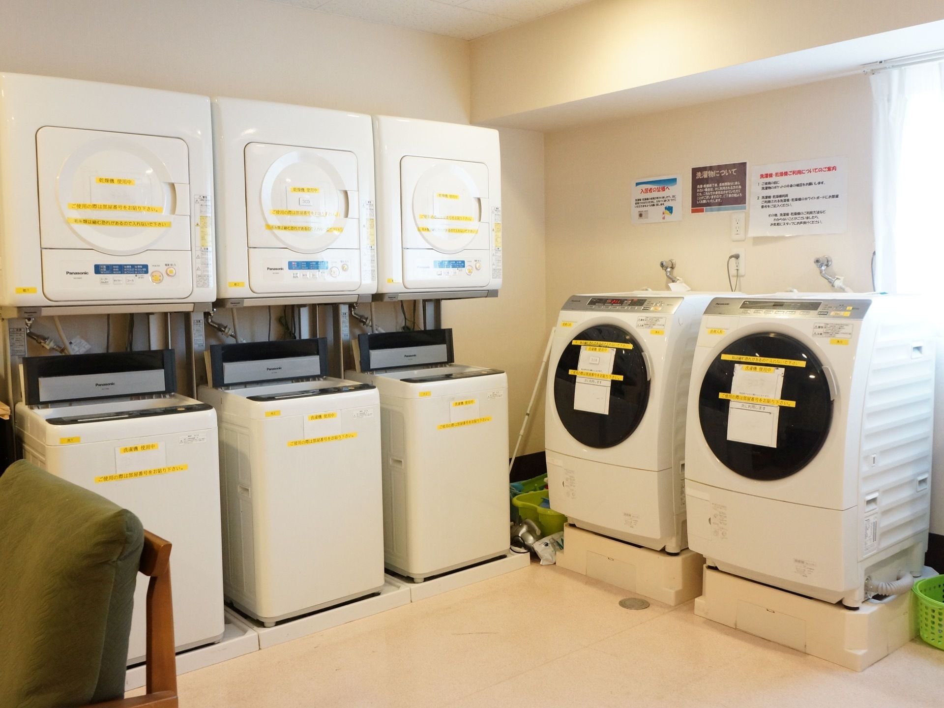 洗濯機と乾燥機がそれぞれ設置されている。各家電のふたや側面には使用方法が印刷された黄色のシールが貼られている。