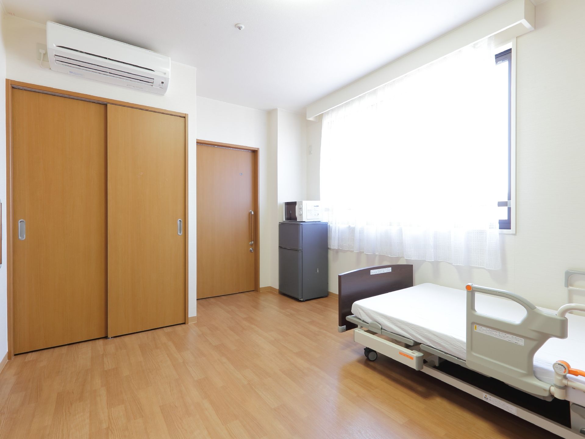 エアコンと火災報知器が設置されている。扉は全てスライド式になっている。床とひと続きになった引き戸の収納スペースがある。