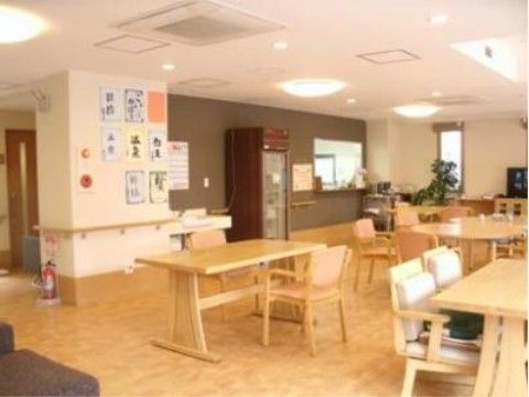 リビングには木製のテーブルと手すり付きの椅子が置かれ、床はフローリングになっている。周囲の壁には手すりが設けられている。