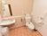 広いトイレスペースに洋式便器と洗面台を設置している。壁には小物棚を設け、消臭芳香剤などの衛生用品を用意している。