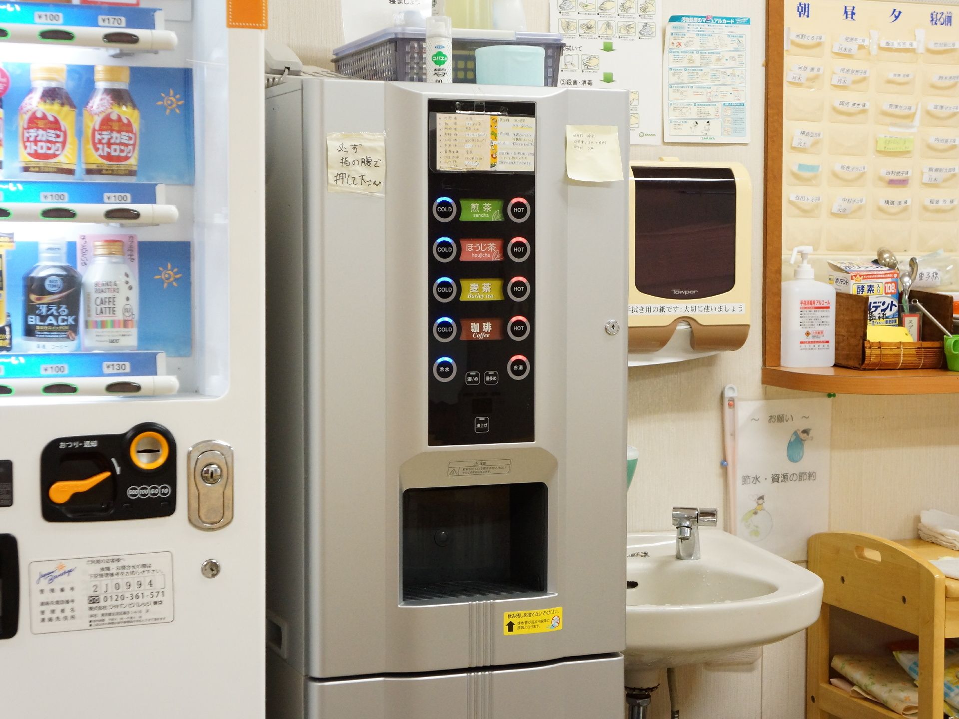 正面の壁際には、緑茶やほうじ茶などのボタンが付いている給茶機が設置されている。その左隣には自動販売機も見える。