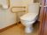 便座が真ん中にあるトイレルームには、その横側に逆コの字型の手すりがある他、トイレットペーパーの付近にも手すりが設置されている。