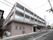 1階は駐車場、2階以上が居住空間になっている。建物の壁に施設名が書かれたプレートが取り付けられている。玄関前に立て看板が置かれている。