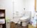 利用者が実際に生活している部屋のトイレの状態。便器周囲に掃除用具やパットなどの衛星用品が置かれている。
