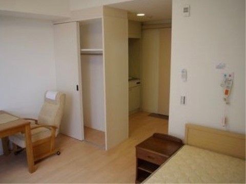 ベッドの横にはサイドテーブルがあり、壁にはナースコールのボタンが掛けられている。部屋にはキッチンが設備されている。