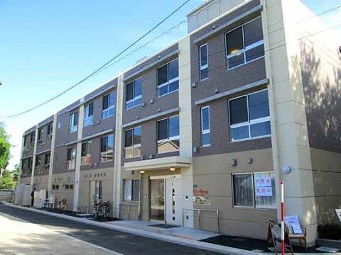 通りに面して居室の窓がたくさん並んでいる３階建ての施設