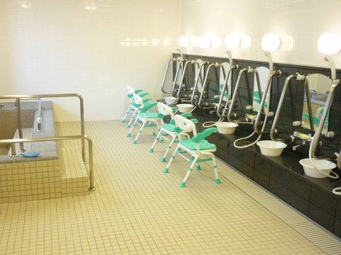 緑のシャワーチェアが置いてある。シャワーチェアを用いることで、浴室でしゃがむ姿勢を取らずに身体や髪の毛を洗える。