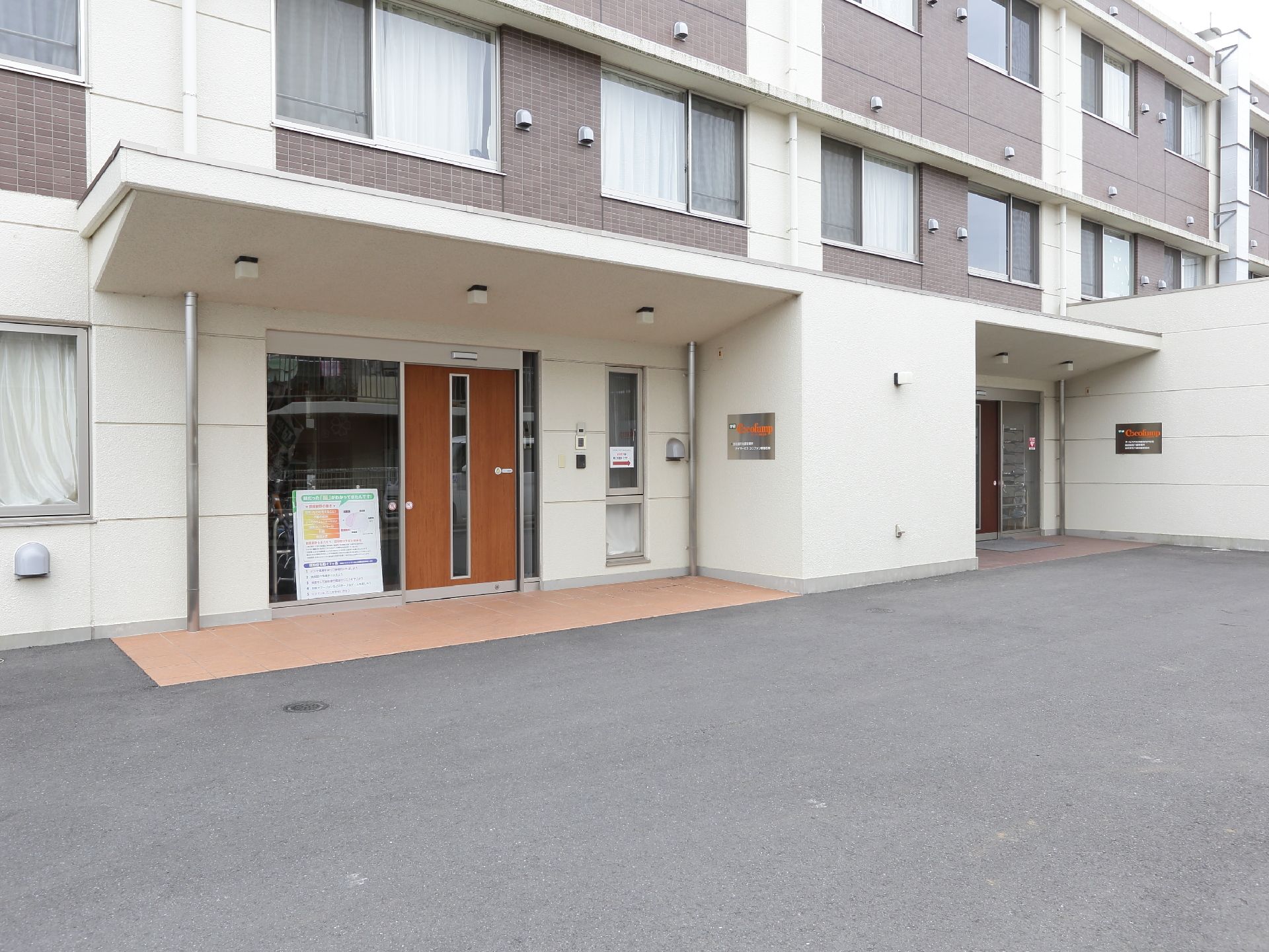施設一階の出入り口はせり出した屋根になっているので雨天時の送迎に配慮されている。出入り口は手前と奥に2つあるのが見える。