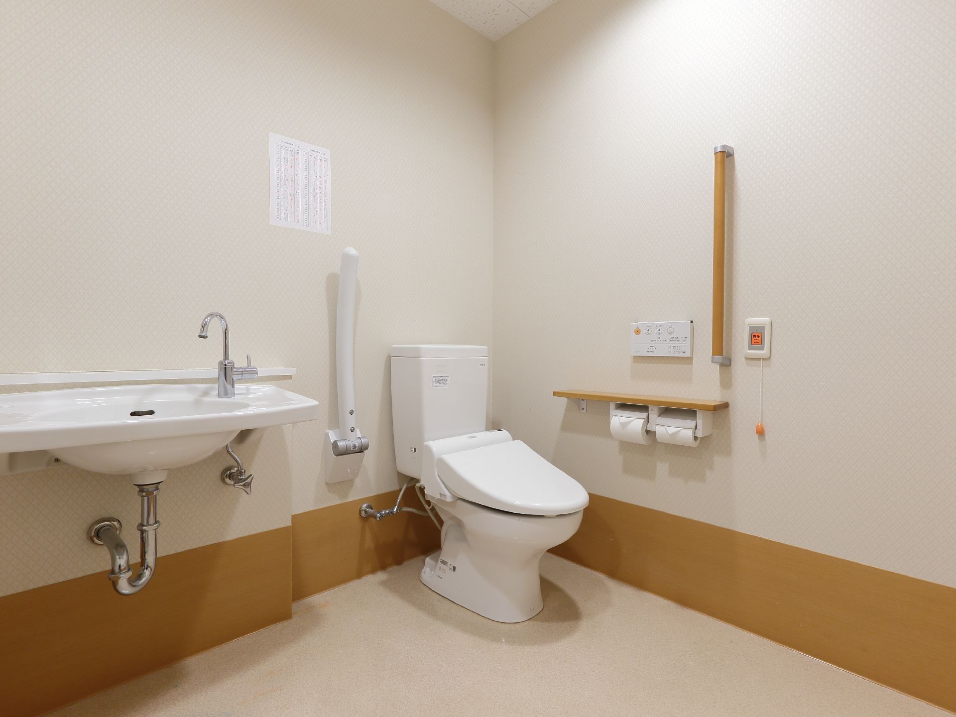 トイレは広々としており、手すりや可動式のひじ掛けがあるので安全である。洗面台も隣りに設置されている。