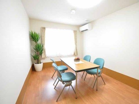 白い壁に茶色のフローリングで、家具が少ないスッキリとした部屋である。観葉植物が置かれ、ゆったり落ち着ける部屋になっている。