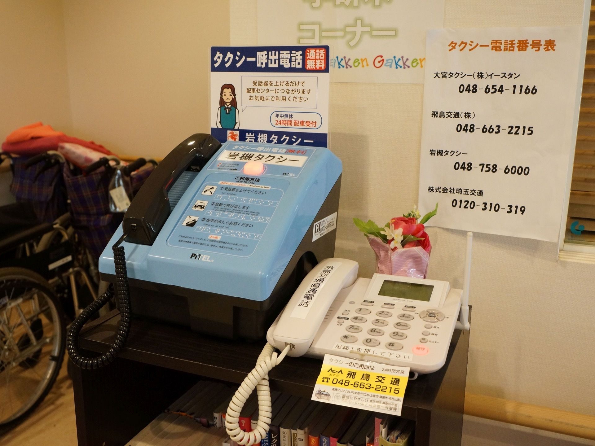カラーボックスの上にタクシーを呼び出す専用の電話が２台置かれている。４社ほどの電話番号を掲示している。