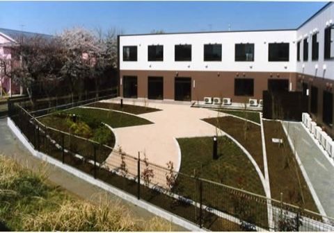 ２色に塗られたＬ字型の建物に囲まれている散歩コースが作られた中庭