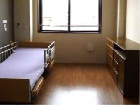 左手の壁際に落下防止柵のついた介護用ベッドのある居室